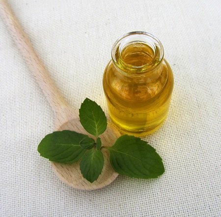 Bottle of peppermint oil with a wooden spoon, close-up