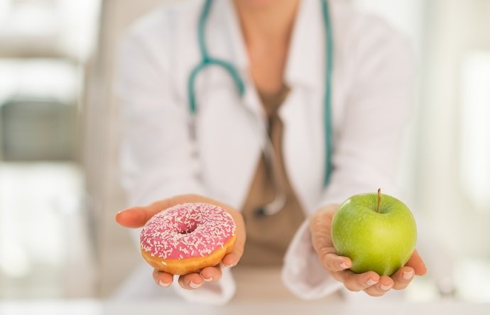 Closeup on medical doctor woman giving a choice between apple and donut