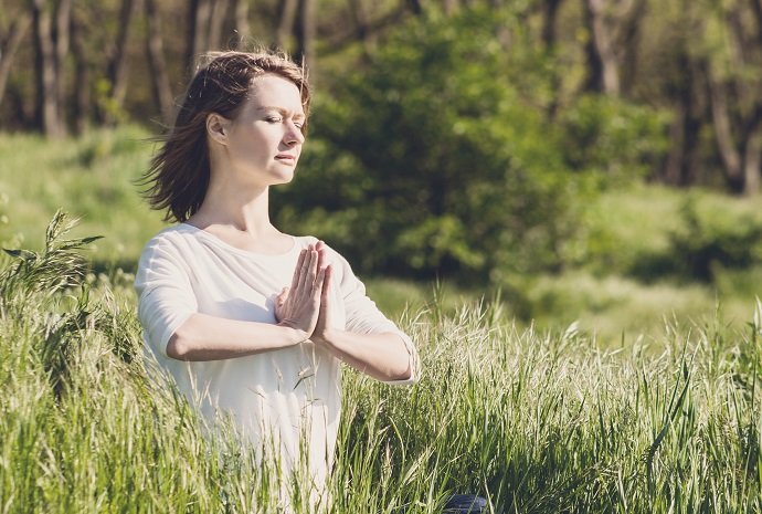 A young woman meditating in park at the sunrise